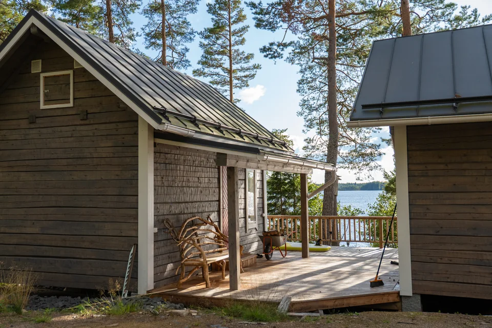 Kaksi puurakennusta metsäisessä pihapiirissä